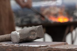 Old,rusty,hammer,lies,on,the,anvil,with,blacksmith,work