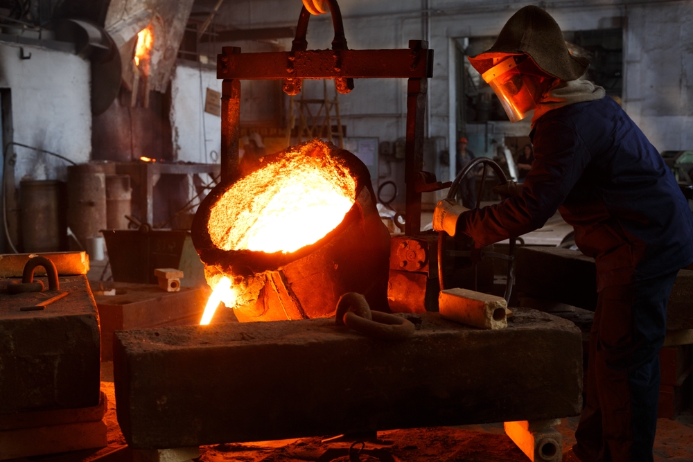 Industrial,worker,in,protective,gear,pours,molten,metal,at,steel